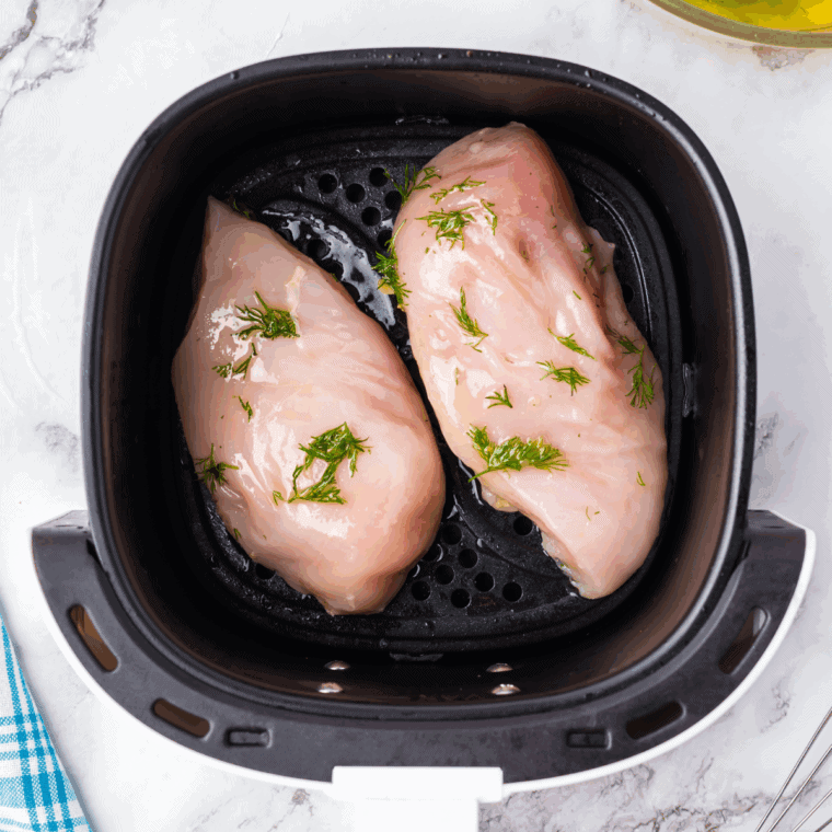 Air Fry the Chicken: Chicken breasts air frying in the air fryer until golden and cooked all the way through.