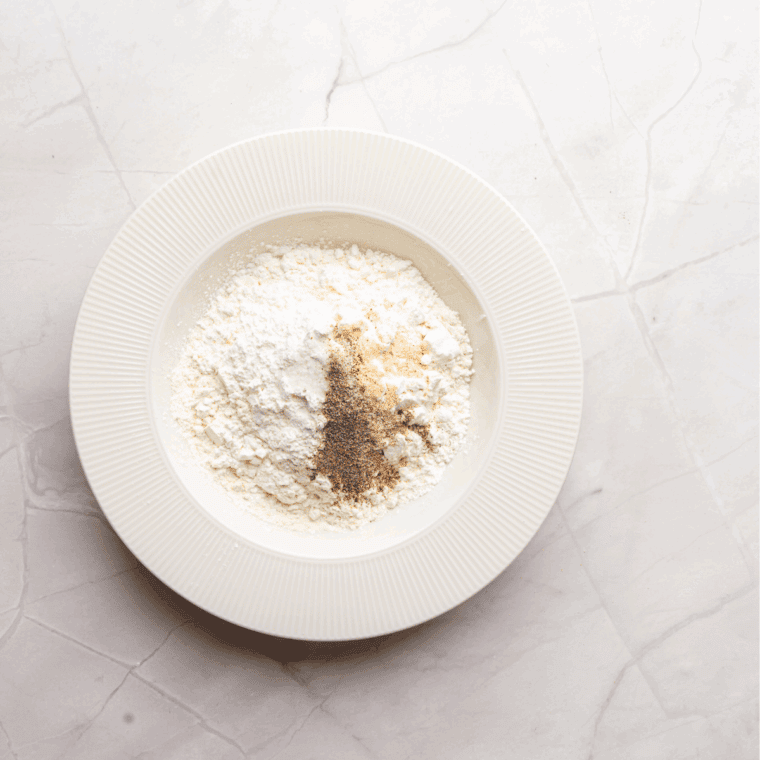 A bowl of seasoned flour mixture with cornstarch, paprika, garlic powder, onion powder, cayenne, salt, and pepper.