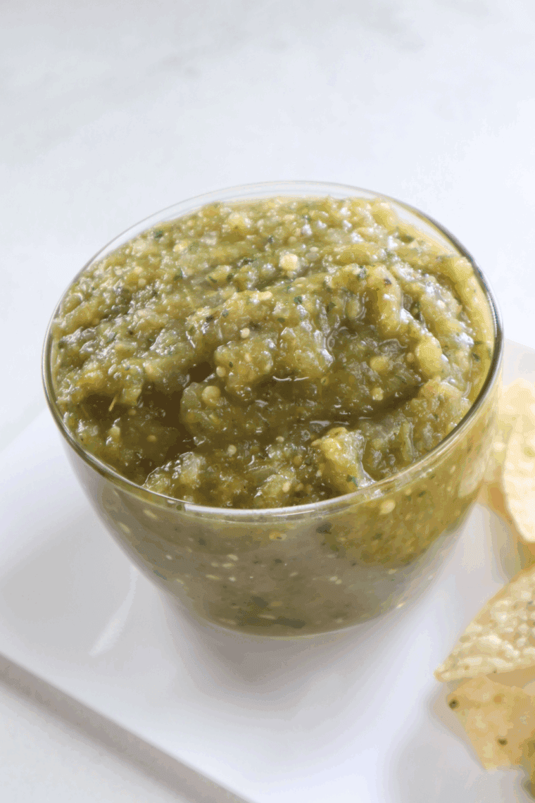 Homemade fresh Tomatillo Salsa imitated by Abuelo is placed in a bowl with tortilla slices.