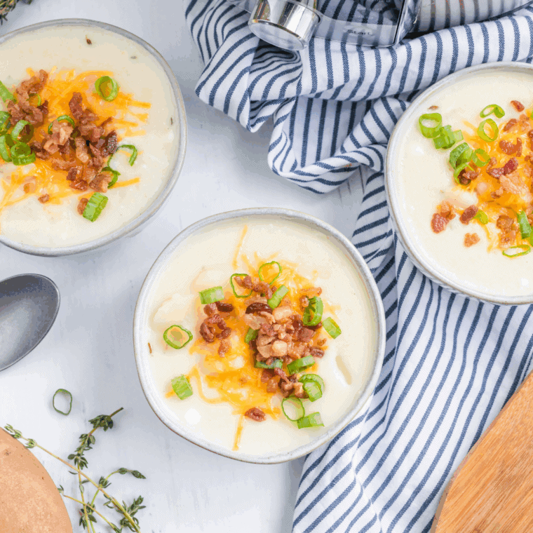 Bowl of Copycat Bob Evan's Cheddar Baked Potato Soup on kitchen counter.