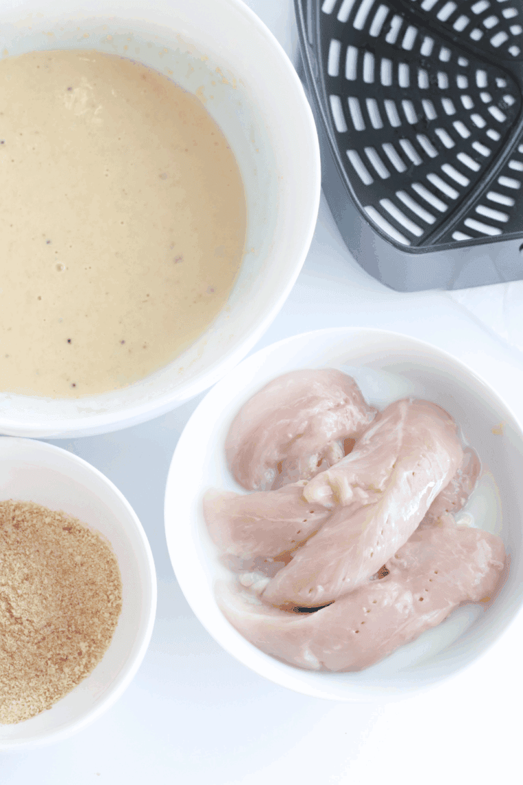 Two bowls side by side—one with seasoned flour mixture, the other with beaten eggs and milk for coating chicken.