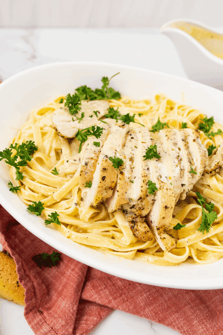 Domino’s-style chicken Alfredo pasta with creamy sauce, grilled chicken, and Parmesan cheese, served on a plate with parsley garnish.