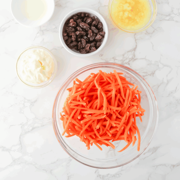 Ingredients needed for Golden Corral Carrot and Raisin Salad on kitchen table.