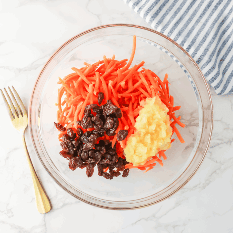 Shredded carrots, raisins, mayo and pineapple in the mixing bowl, prepared for mixing.