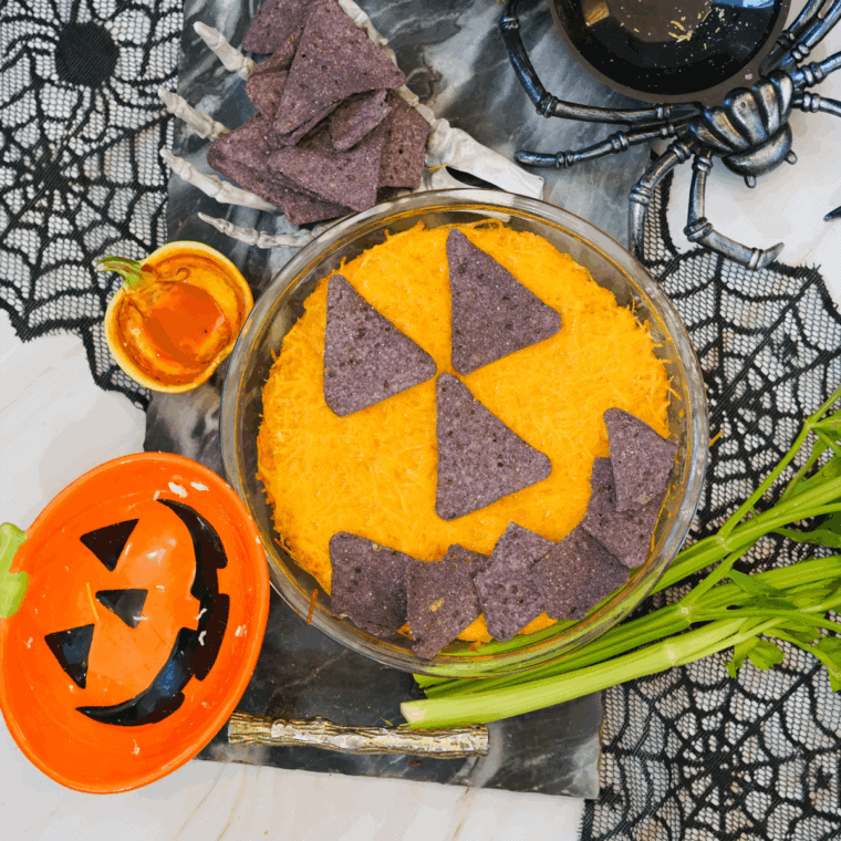 Halloween boo wings dipped in a baking dish, decorated with celery “stems” and tortilla crumbs pumpkin faces.