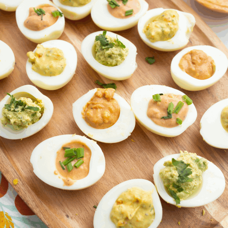 Classic Ina Garten deviled eggs with creamy filling, garnished with paprika and parsley on a serving platter.