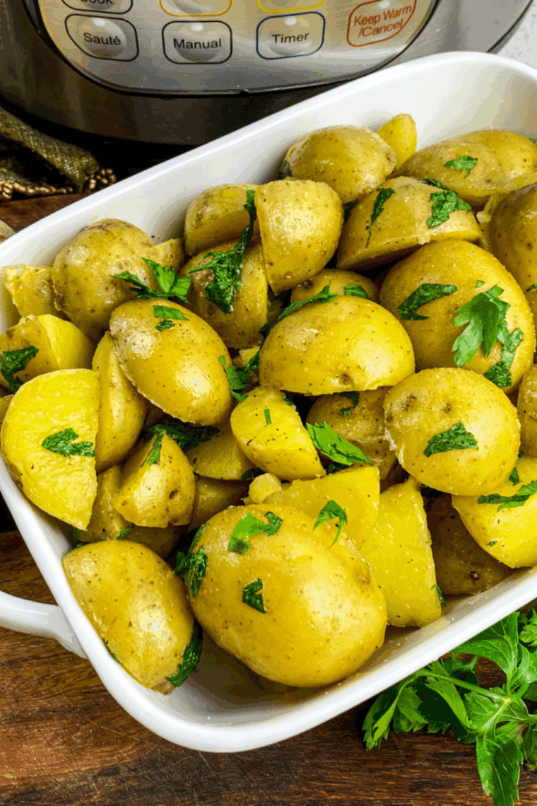 Plate of seasoned Instant Pot Diced Potatoes on the kitchen table. With the Instant Pot in the background.