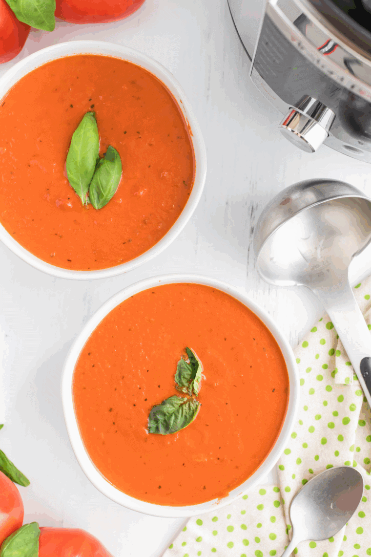 Instant Pot Madeleine Tomato Basil Soup served in a bowl, garnished with fresh basil and paired with crusty bread.
