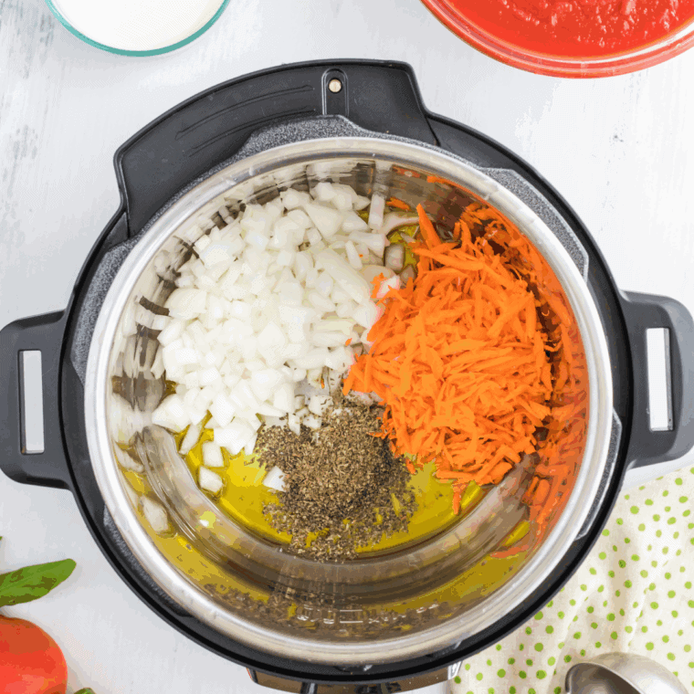 Onions, garlic, carrots, and celery sautéing in an Instant Pot with olive oil until tender and fragrant.