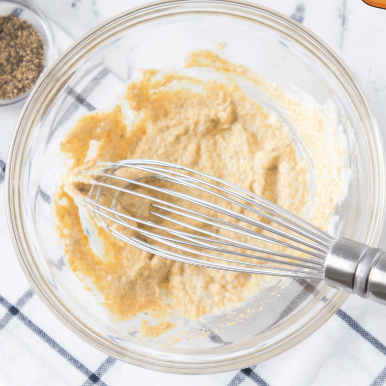 Mayonnaise and seasonings being mixed for chicken salad dressing.