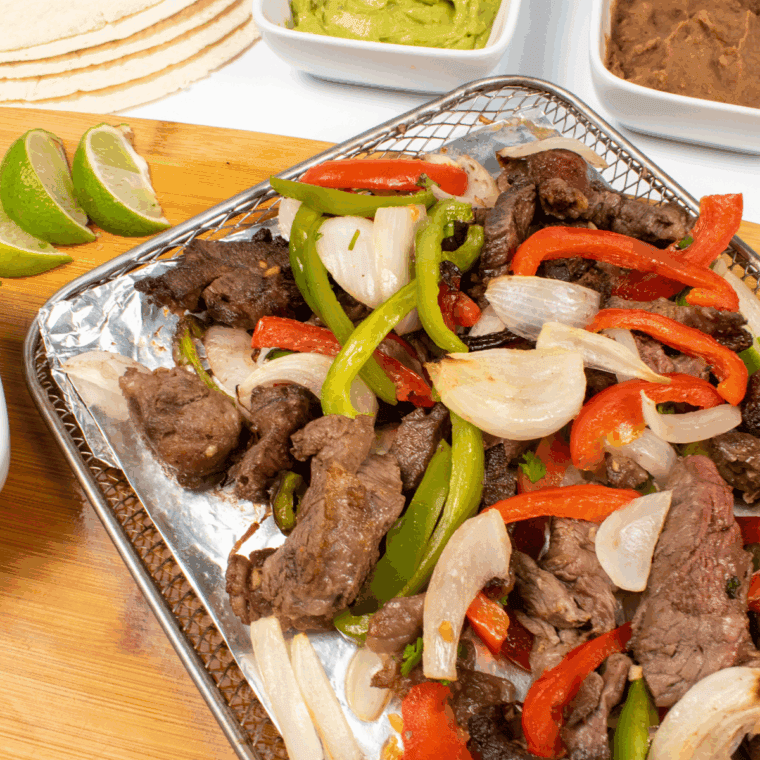 Homemade Lupe Tortilla fajitas with tender marinated steak, grilled peppers, onions, and warm tortillas.