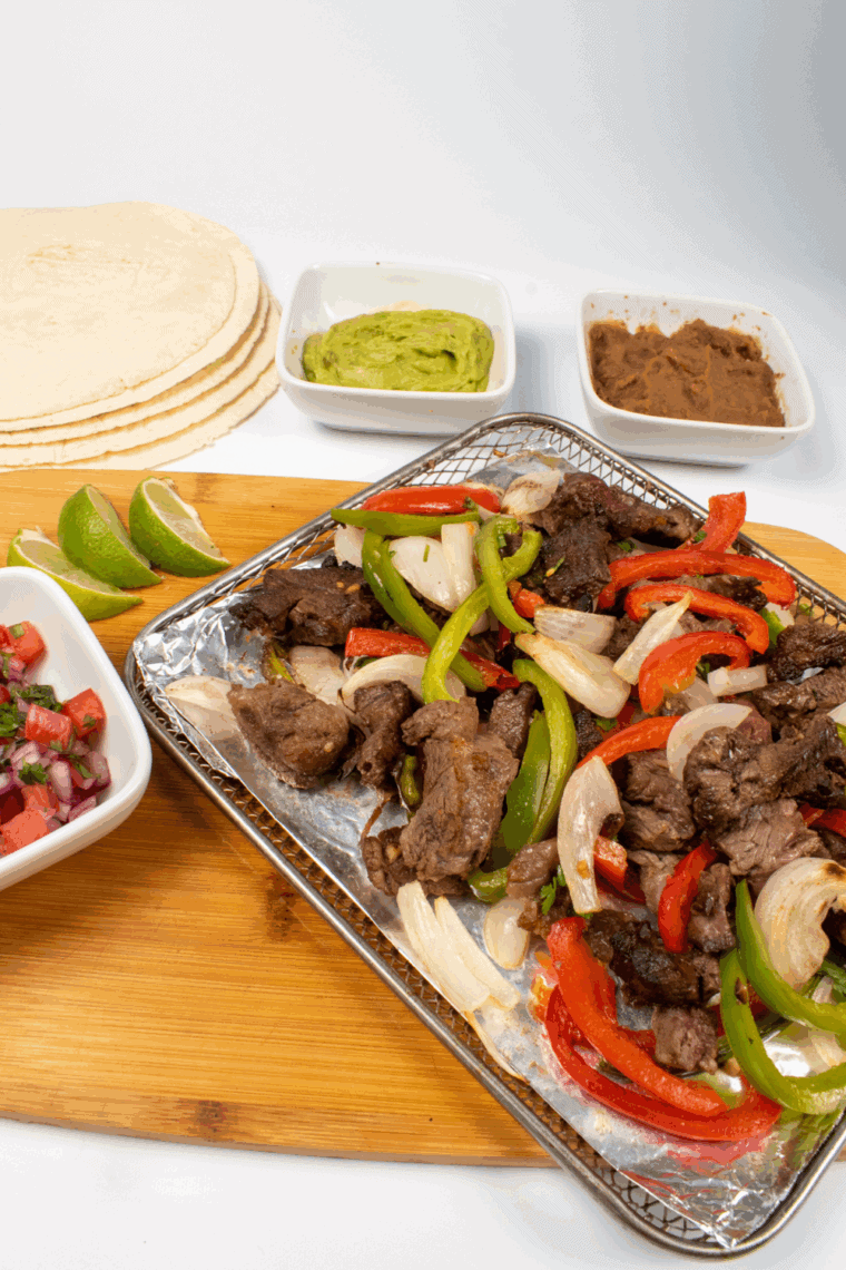 Juicy Lupe Tortilla copycat fajitas with marinated steak, grilled peppers, and onions on a hot skillet.