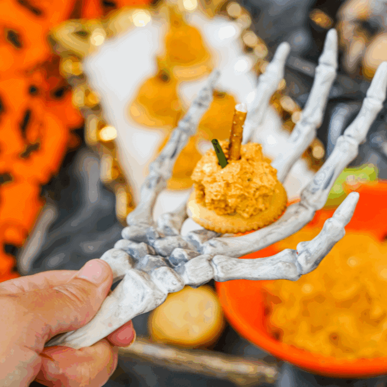 Mini pumpkin-shaped cheese balls on the cookies topped with pretzel stems and green onions for use as a festive fall appetizer.