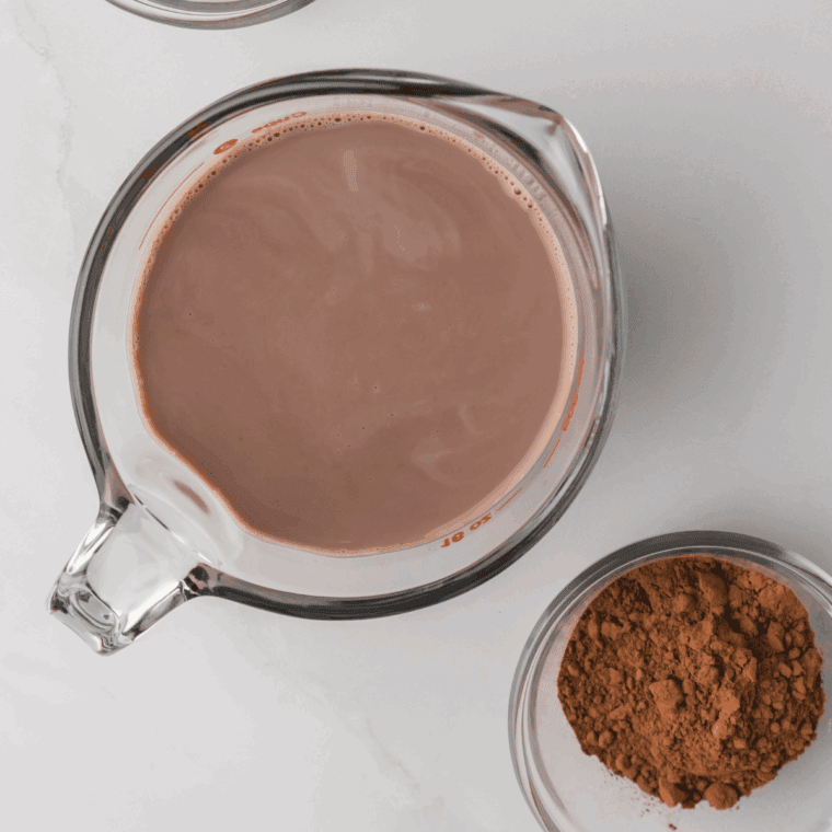 Whisking heavy cream, milk, sugar, cocoa powder, and vanilla extract in a large mixing bowl for Ninja Creami Blue Bell Dutch Chocolate ice cream base.