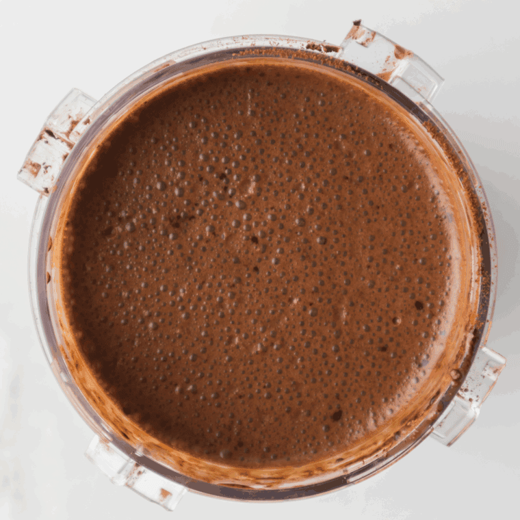 Chocolate ice cream mixture being poured into a Ninja Creami pint container, leaving headspace before covering and freezing upright for 24 hours.