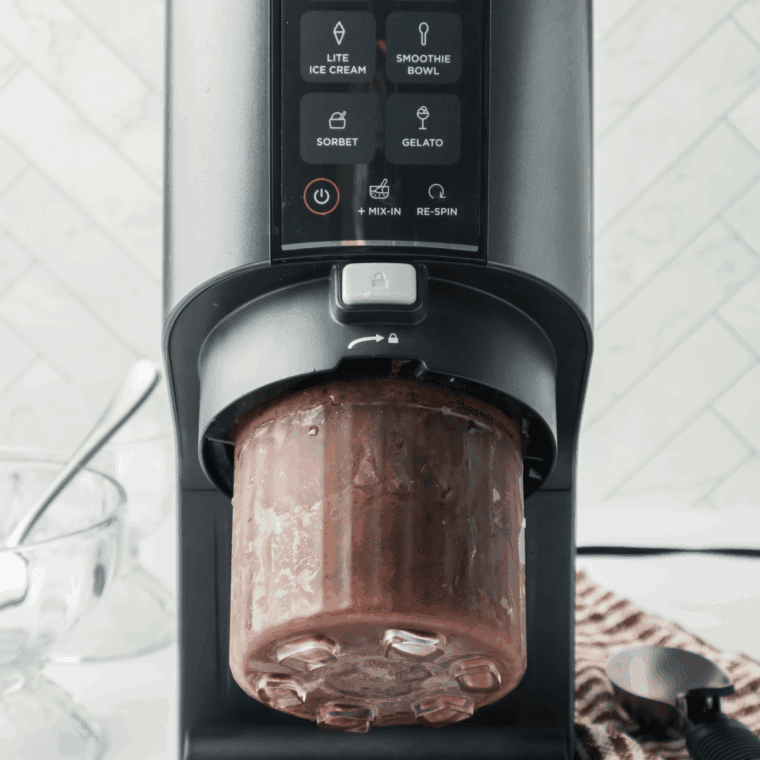 Frozen chocolate ice cream pint in a Ninja Creami machine on the Ice Cream setting, with chocolate chips added and mixed in for extra creaminess.