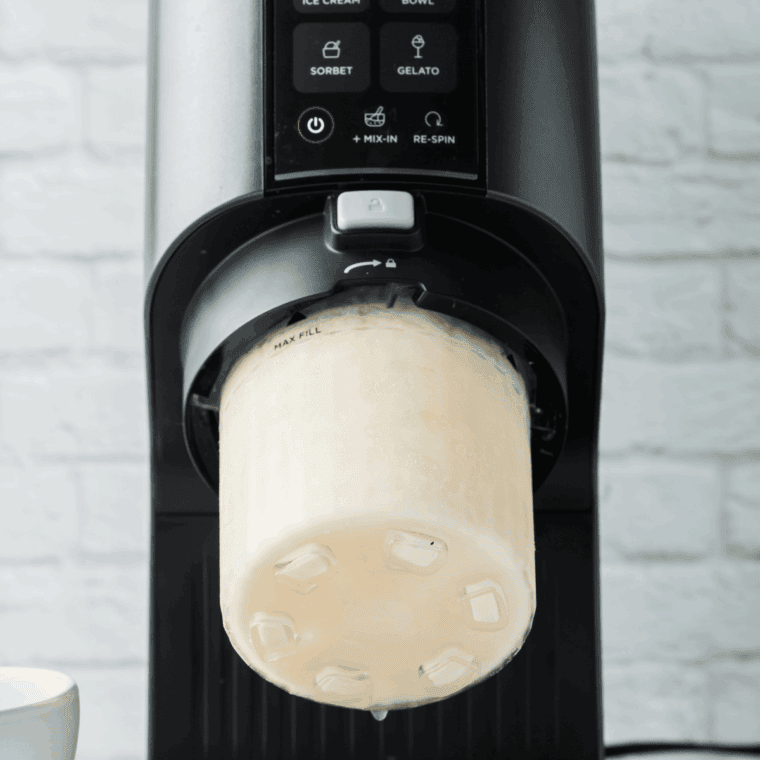 Frozen pint in Ninja Creami machine, churning creamy ice cream.