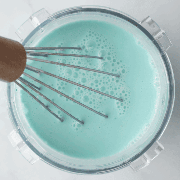 Mixing granulated sugar, vanilla extract, dry ice cream mix, milk, and heavy cream in a pint container with blue food coloring for Cookie Monster ice cream base.