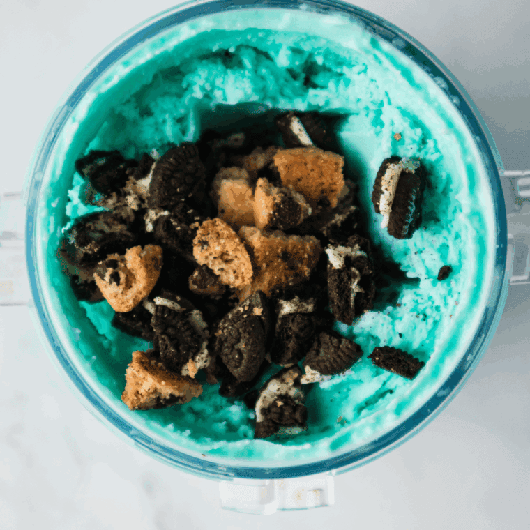 Scooping creamy Cookie Monster ice cream into bowls for soft-serve or firmer texture after additional freezing.