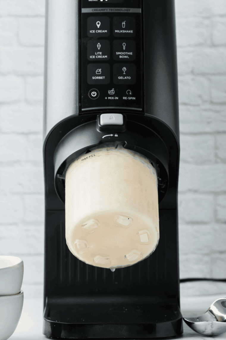 Churning frozen mixture in Ninja Creami for creamy soft-serve texture with mix-ins.