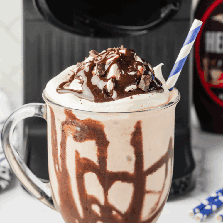 Finished Ninja Creami Mocha MooLatte topped with whipped cream and chocolate drizzle in a tall glass.