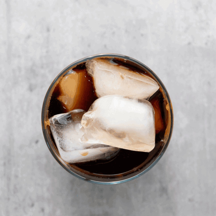 Pouring chilled coffee over ice and adding milk or cream.