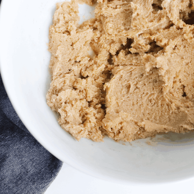 Mixing peanut butter, sugars, eggs, and vanilla into smooth cookie dough.