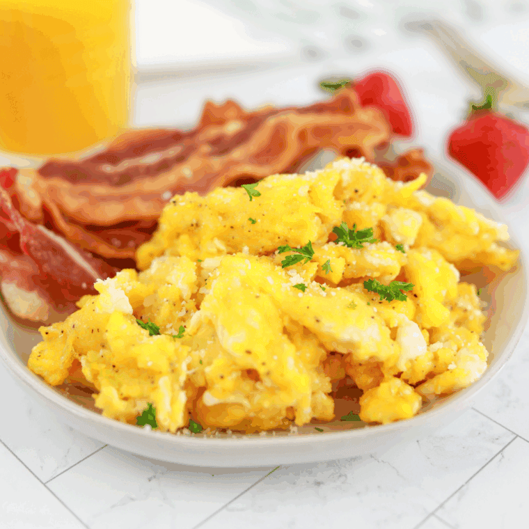 Plate of Waffle House Scrambled Eggs on kitchen table. with bacon and orange juice.