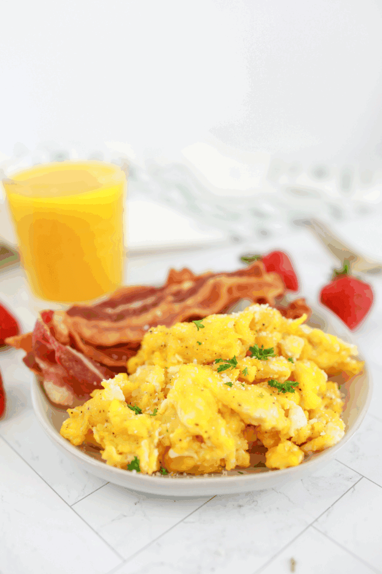 Plate of Waffle House Scrambled Eggs Recipe with bacon and on a table.