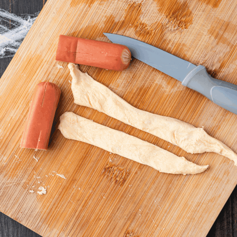 Crescent roll dough wrapped around center of hot dog, pinched at back to secure.