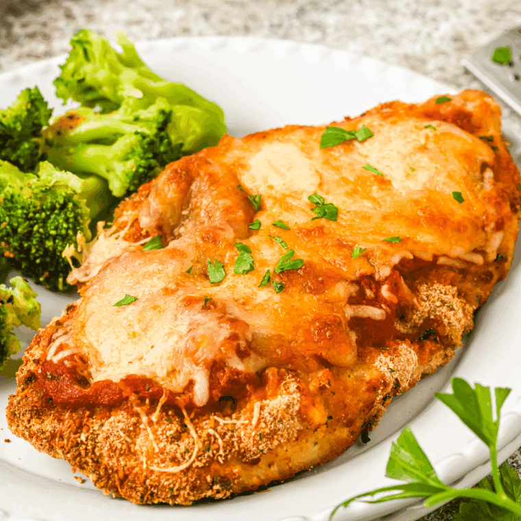 Golden crispy Barefoot Contessa Chicken Parmesan topped with marinara sauce and melted mozzarella cheese, served with fresh herbs.