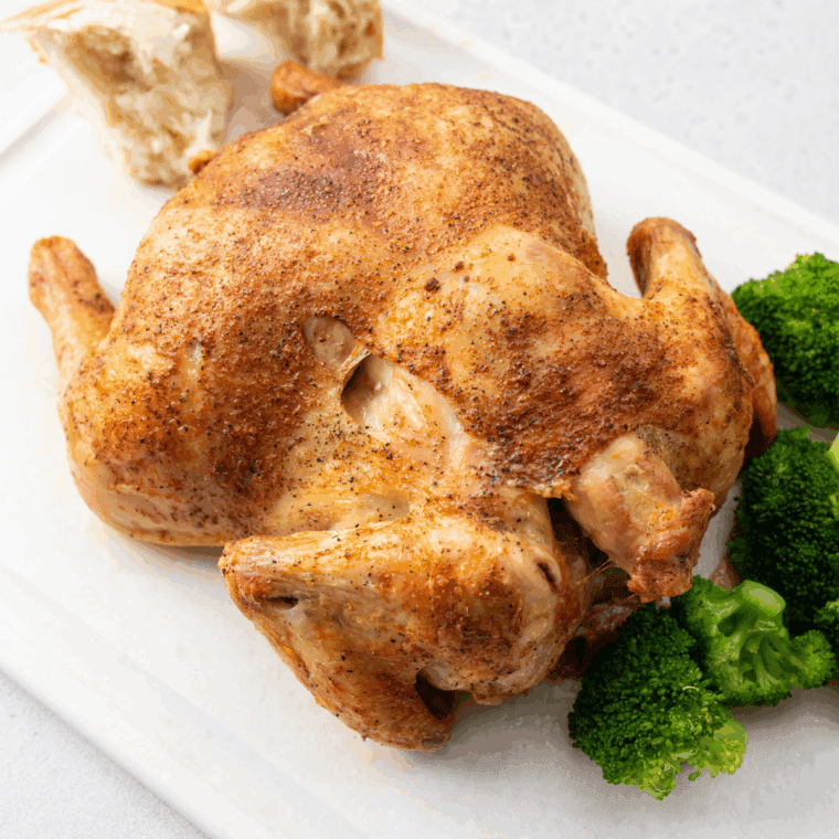 Golden roasted Barefoot Contessa Cornish Hen on a serving platter with herbs and lemon.