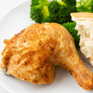 Golden roasted Barefoot Contessa Cornish Hen served on a platter with herbs.
