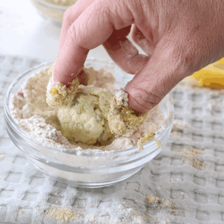Coating cheese balls by rolling in flour, egg, and breadcrumbs for frying.