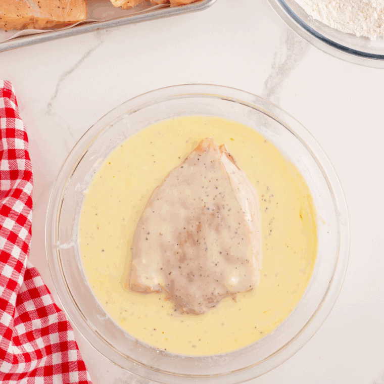 Chicken breasts soaking in buttermilk to tenderize and enhance flavor before frying.