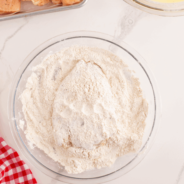 Mixing flour, cornstarch, and spices in a shallow bowl to create a crispy chicken coating.