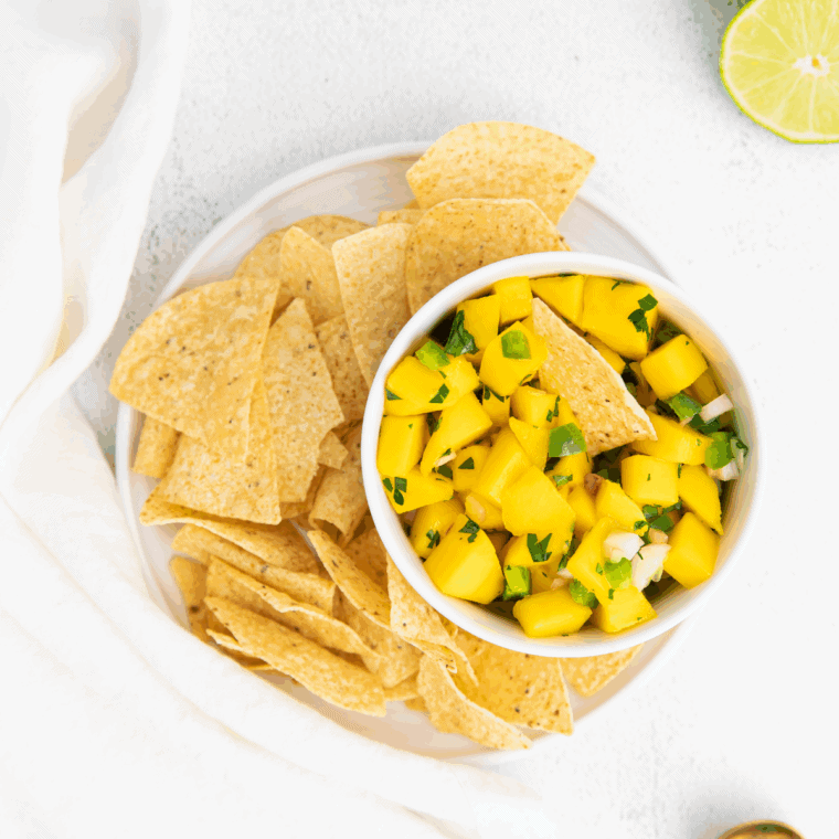 Bowl of colorful mango salsa with diced mango, red bell pepper, jalapeño, red onion, and fresh cilantro.