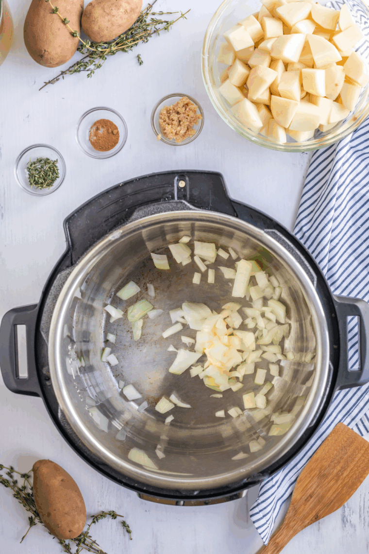 Instant Pot on Sauté mode with butter, onions, celery, and carrots cooking, garlic added for flavor.