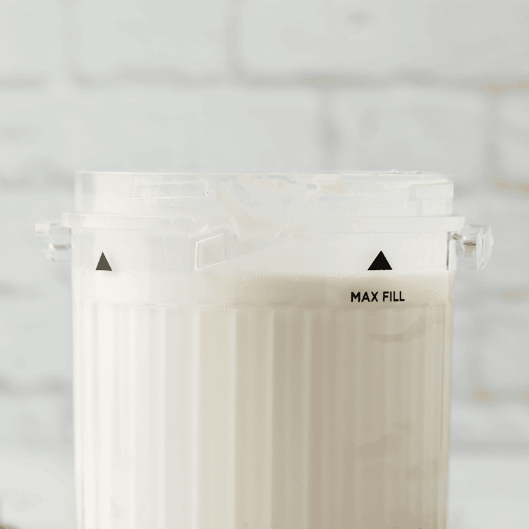 Vanilla ice cream, milk, and maple syrup added to Ninja Creami pint container, ready to mix.