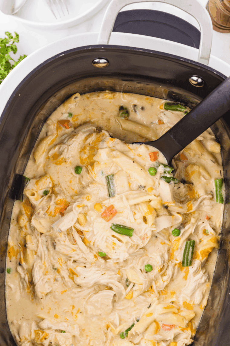 Crock Pot Chicken Pot Pie Pasta with shredded chicken, rotini, mixed vegetables, and melted cheese in a creamy sauce.