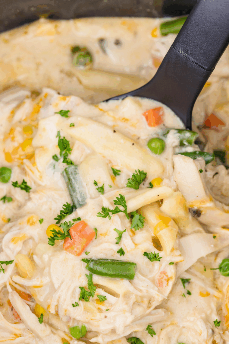 Crock Pot Chicken Pot Pie Pasta with shredded chicken, rotini, mixed vegetables, and melted cheese in creamy sauce.