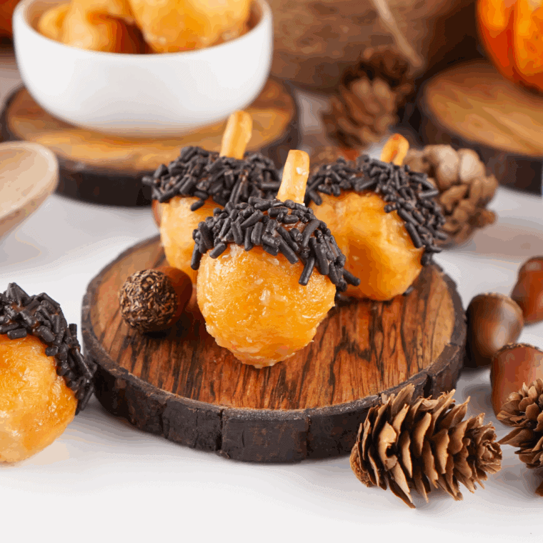 Plate of soft, spiced acorn-shaped donut holes decorated with chocolate and crushed nuts.
