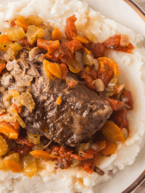 Plate of Easy Agnello Brasato (Braised Lamb) served with rich red wine sauce and herbs.