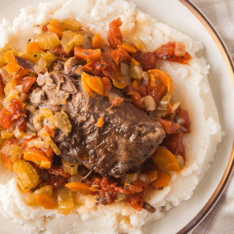 Plate of Easy Agnello Brasato (Braised Lamb) served with rich red wine sauce and herbs.