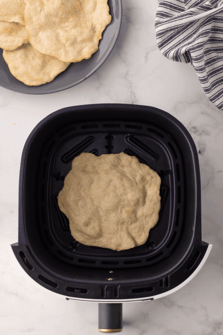 Golden, freshly made air fryer homemade flour tortillas piled on a kitchen towel.