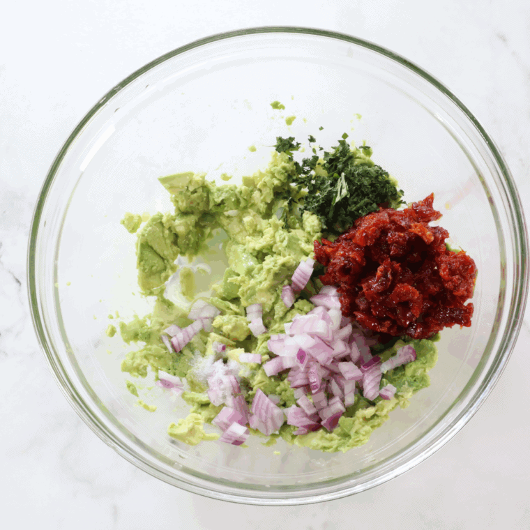 Gently combine diced avocado, sun-dried tomatoes, red onion, cilantro, lime juice, salt, and pepper in a bowl.
