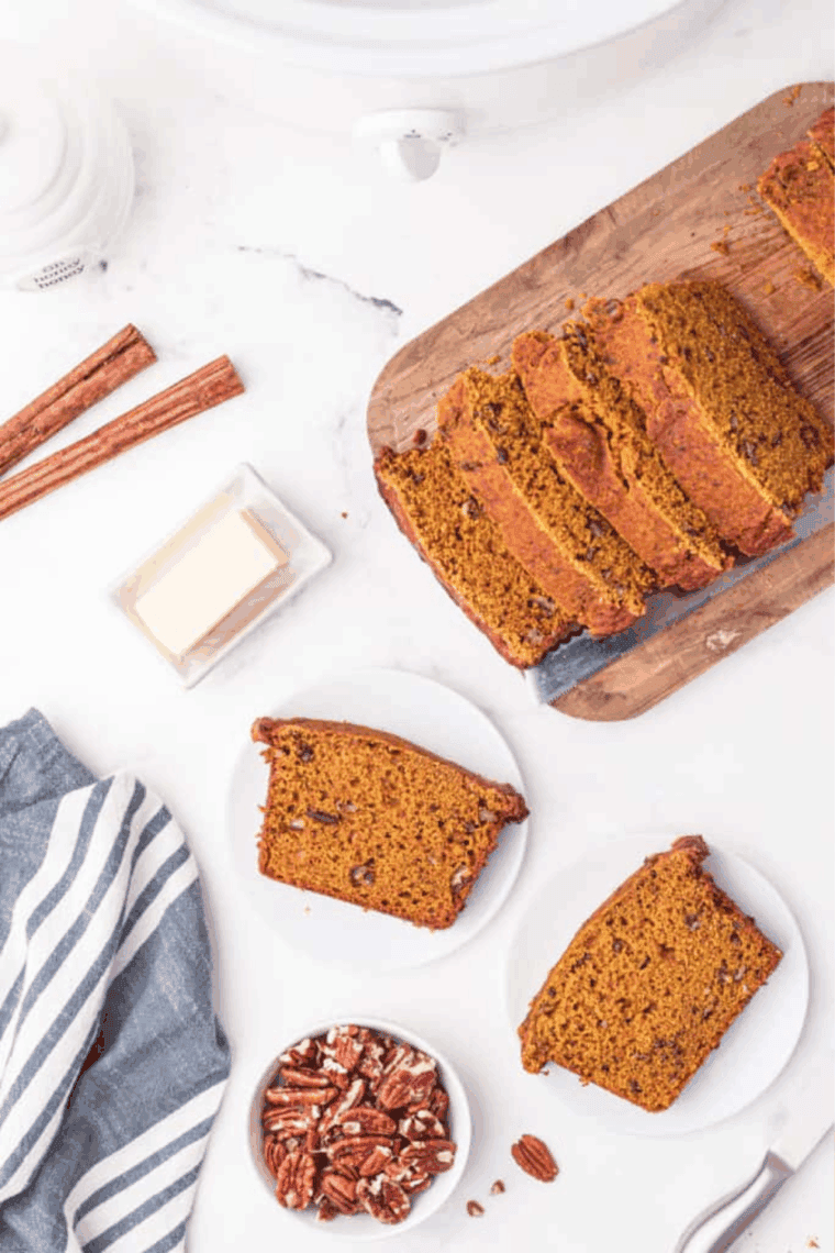 Loaf of Easy Cardamom Pumpkin Bread with golden crust, sliced, showing moist, spiced interior.