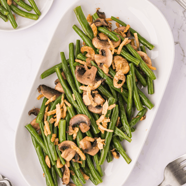 Fresh green beans sautéed in a cast iron skillet with garlic, olive oil, salt, and pepper, served as a flavorful side dish.