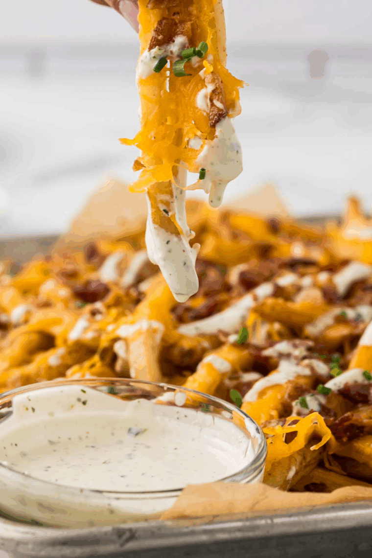 Creamy Cheesecake Factory Ranch Dressing served in a small bowl with fresh herbs on top and a spoon beside it.