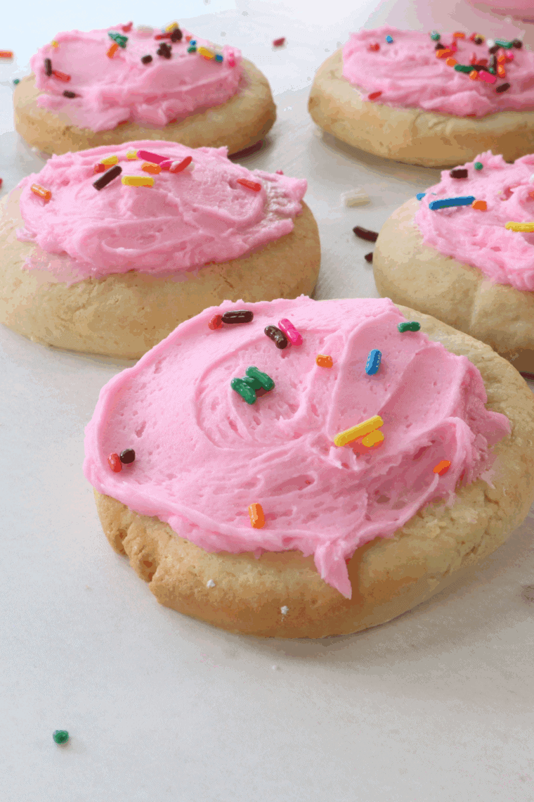 Soft pink-frosted Copycat Crumbl Sugar Cookies on a baking rack ready to serve.